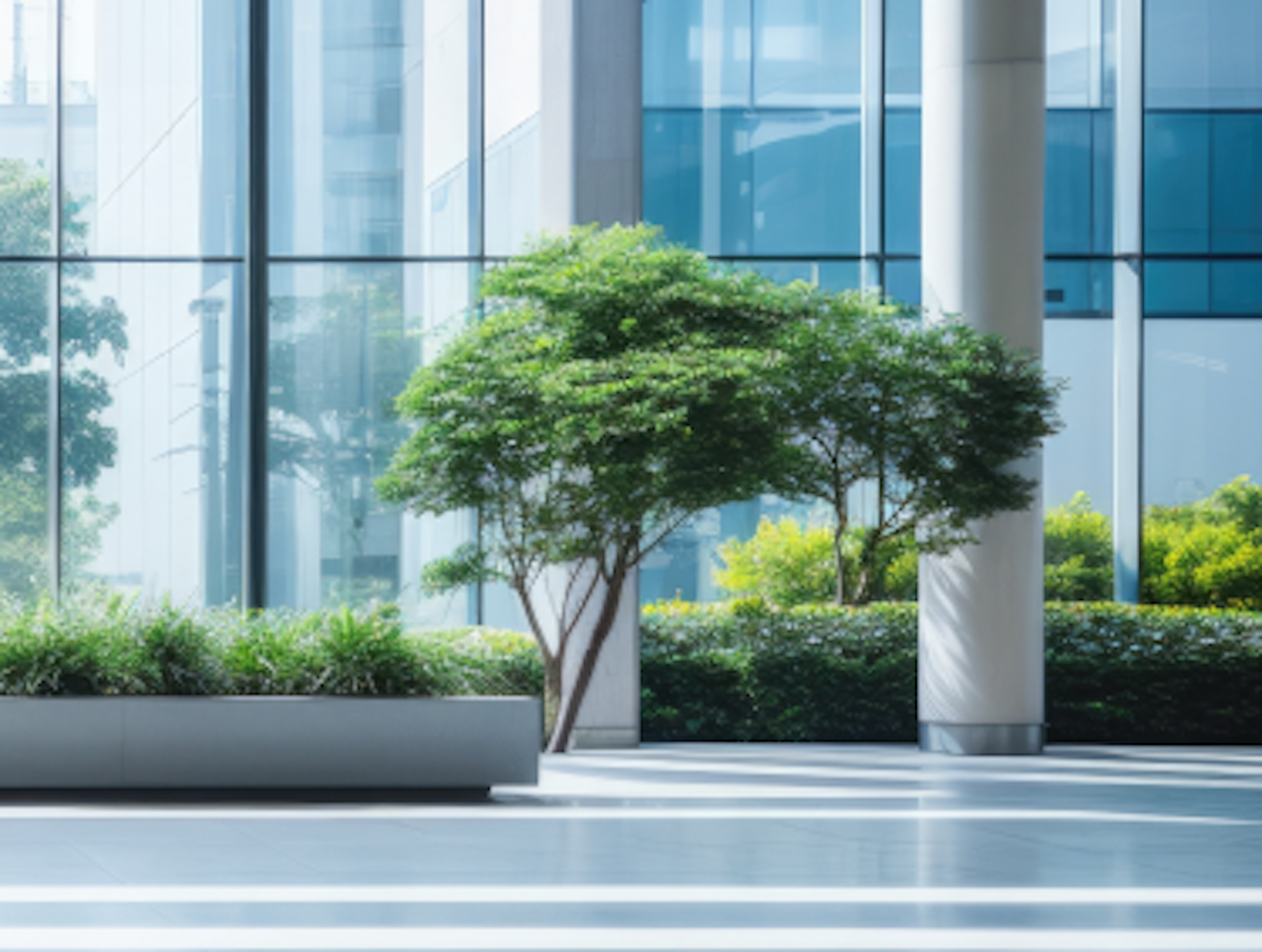 A modern building interior with large glass windows, trees, and plants.