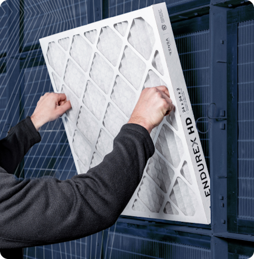 Person installing a new air filter labeled Endurex HD into a ventilation system.