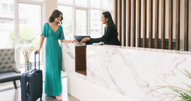 Two women talking to each other in a hotel lobby. Hotel's are large businesses that rely on high-quality commercial air filters to ensure air is clean and fresh for guests.